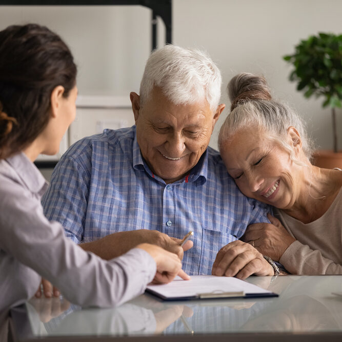 Reaching an agreement. Happy old spouses visiting lawyer broker realtor to buy real estate sign insurance policy create will. Excited aged married couple clients sign financial deal with bank manager